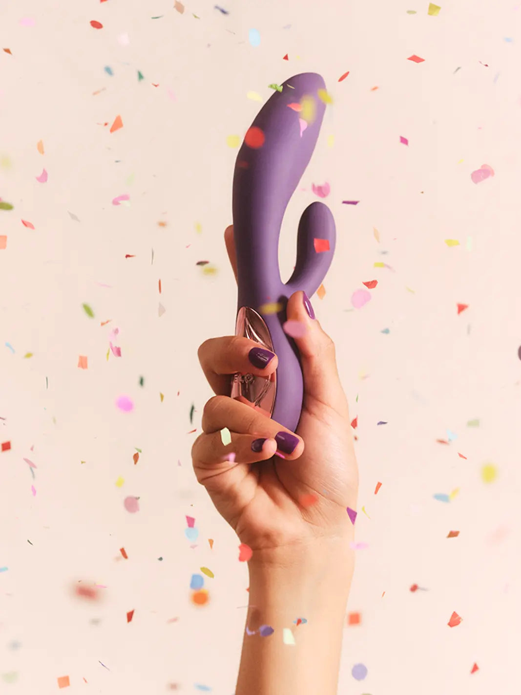 LELO Ina Thrust purple lifestyle image held against a soft confetti background.