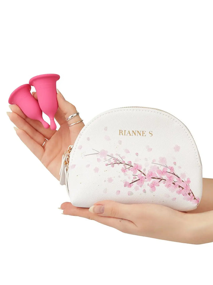 Rianne S Femcare Cherry Cup shown in hand with floral storage pouch and soft pink cup design.