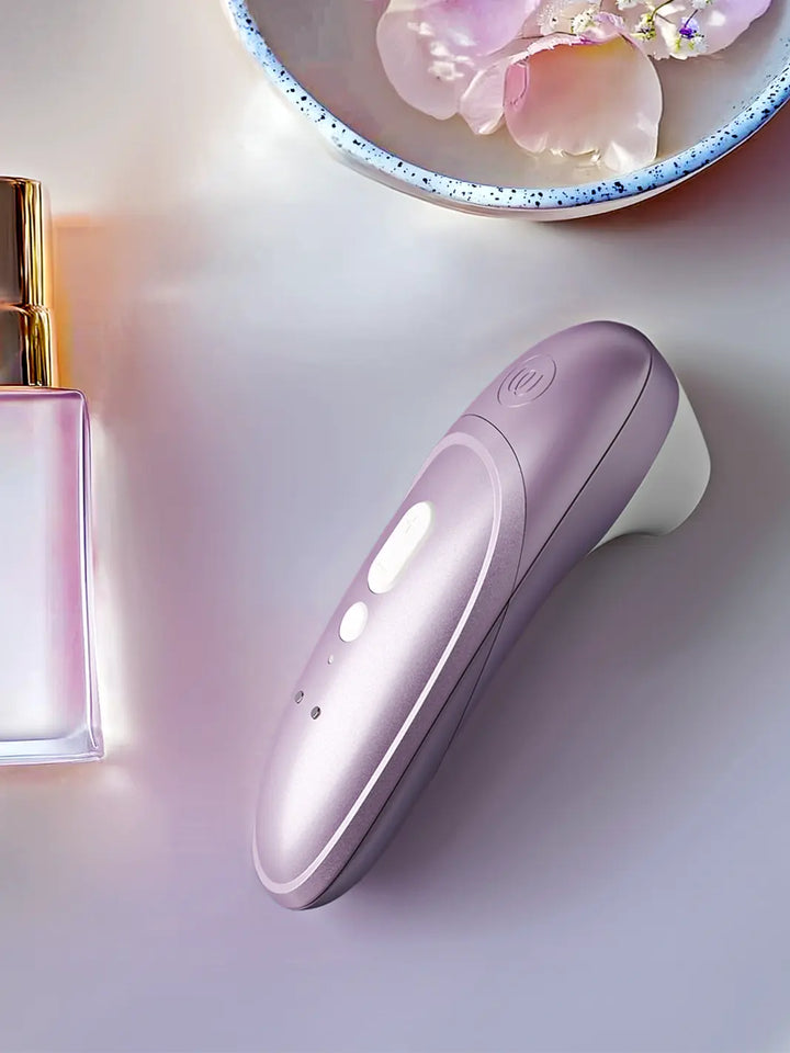 Womanizer Pro lilac placed on a smooth reflective surface in a premium lifestyle setting.