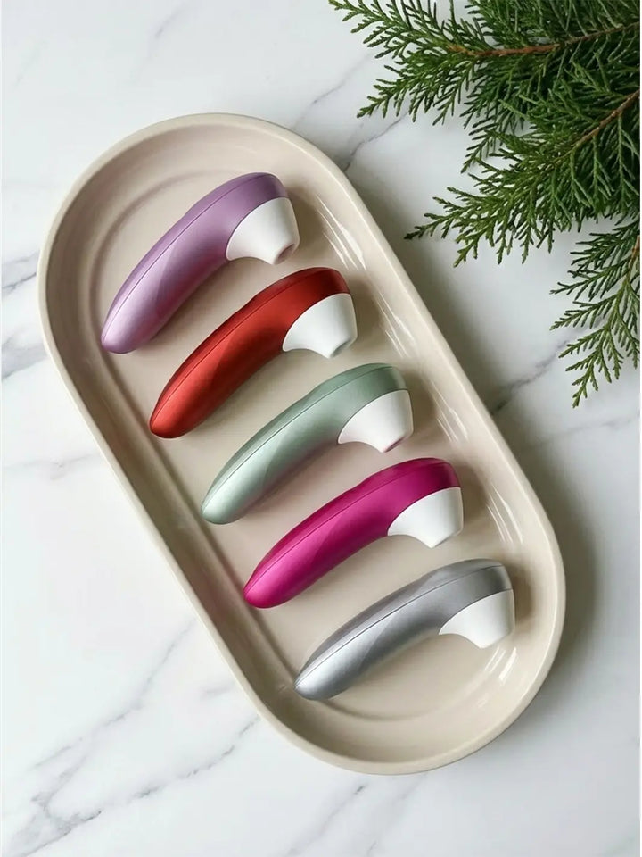 Womanizer Pro in multiple colours arranged in a tray with elegant lifestyle styling.